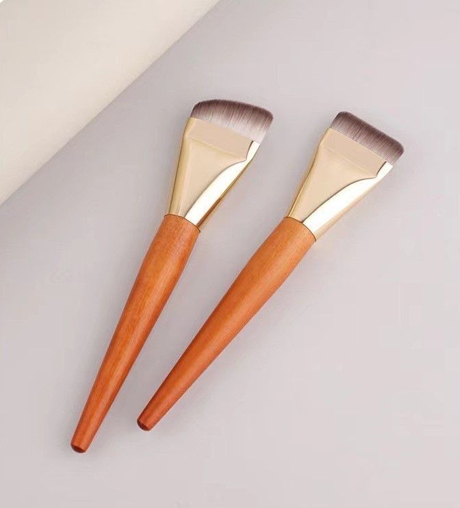 兩把木柄金色箍粉底刷並排擺放在淺色背景上。