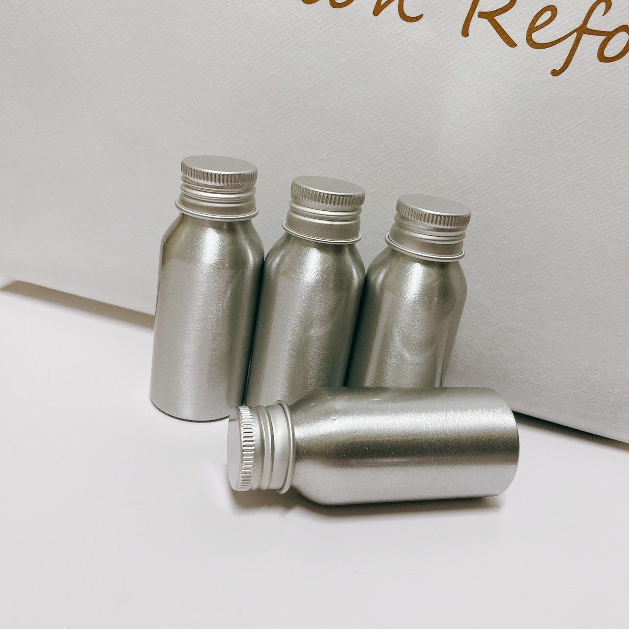 四個小型銀色金屬瓶，瓶蓋為螺旋蓋，其中三個直立放置，一個橫放。
