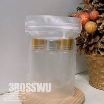 一個磨砂可密封塑膠袋，內裝三個帶有金色瓶蓋的小透明瓶子，放置在木質表面上。