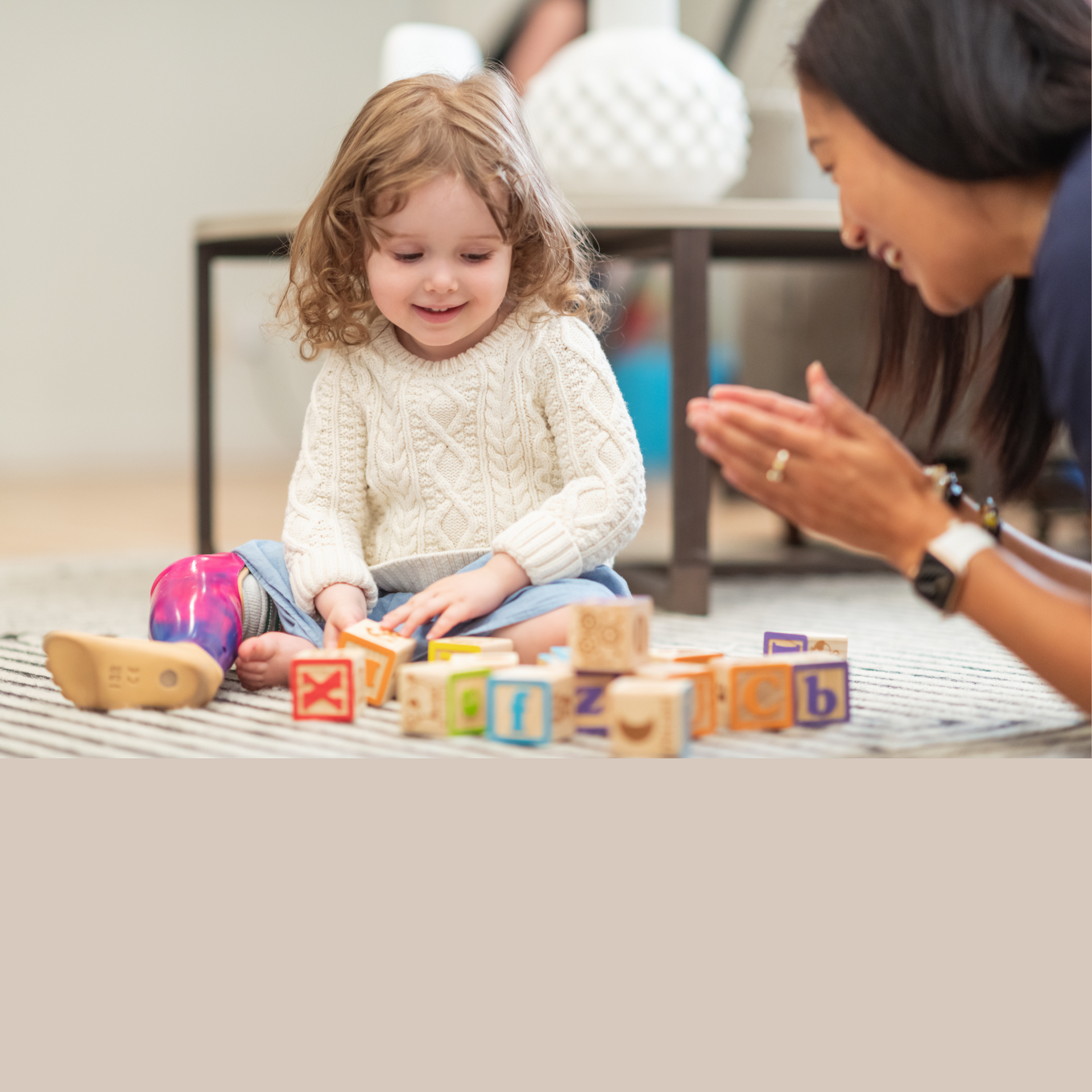 A little girl is sitting on the floor playing with wooden blocks.