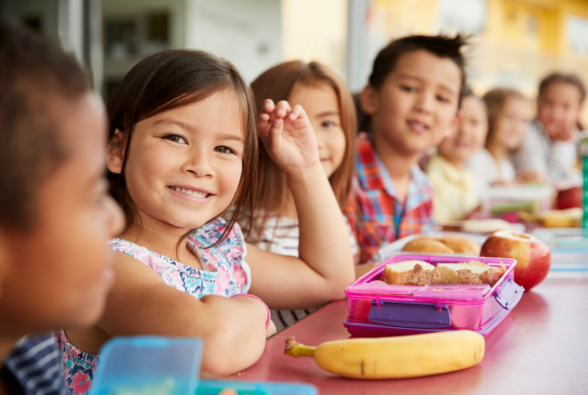A group of children are sitting at a table eating lunch.
