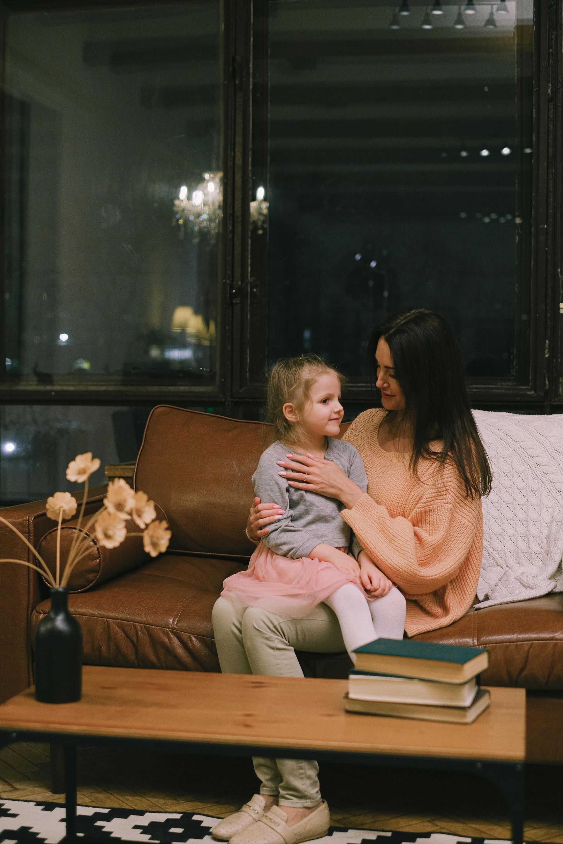 A woman is sitting on a couch holding a little girl.