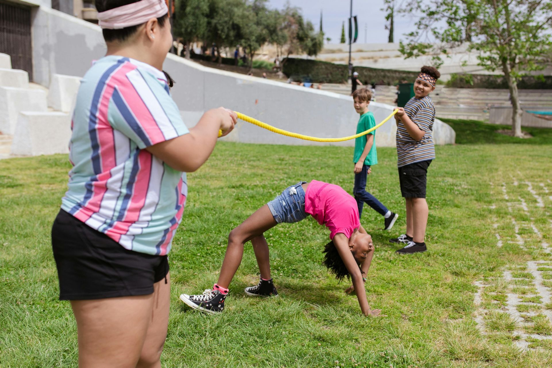 A group of children are playing with a rope in a park.