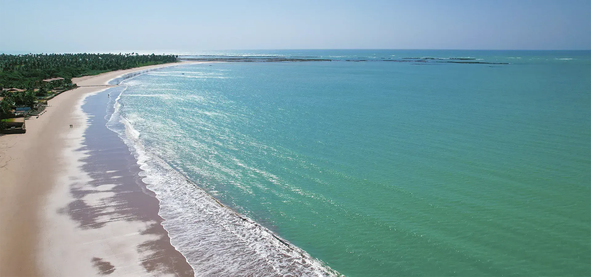 Uma vista aérea de uma praia com ondas batendo na costa.