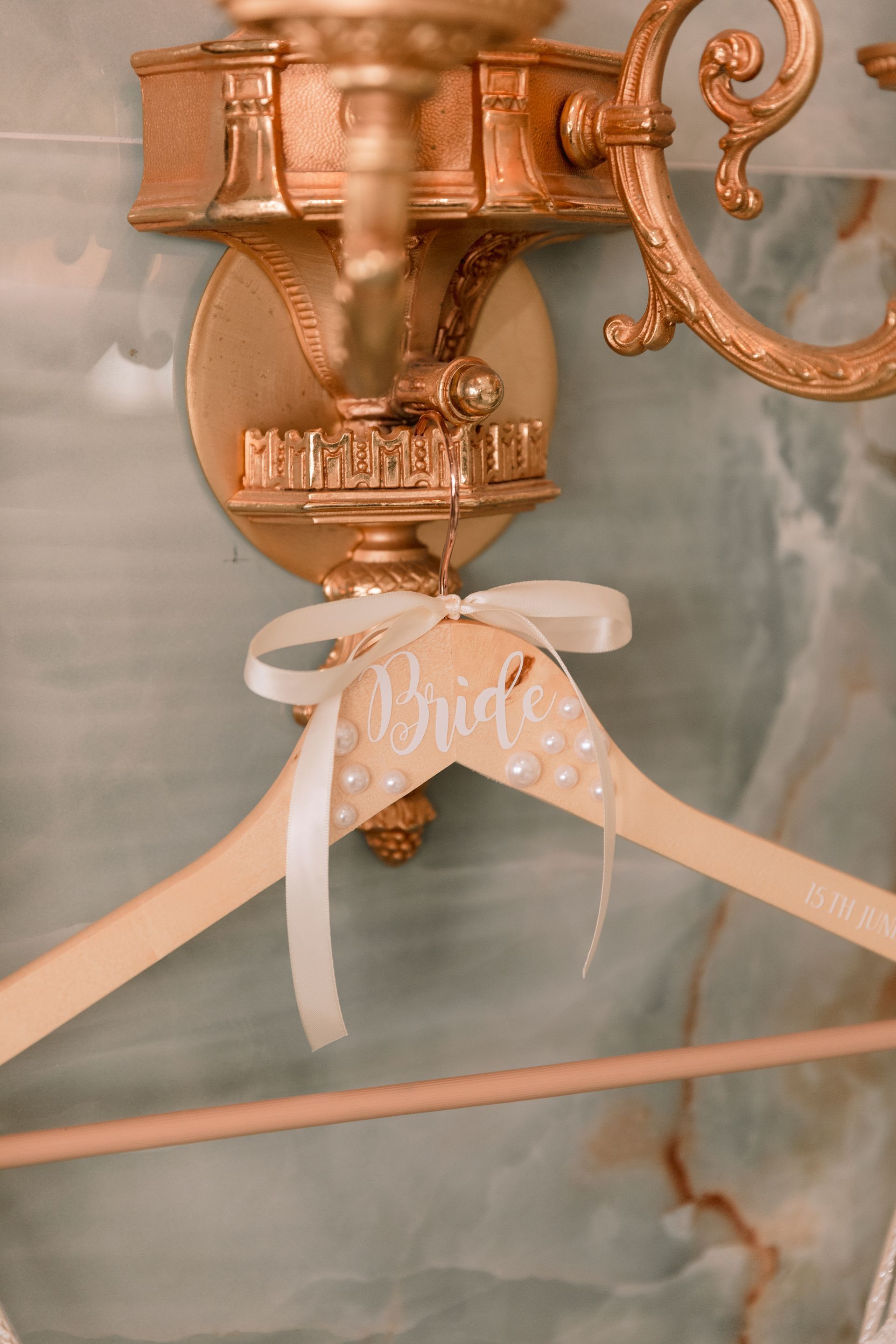 A wooden hanger with the word bride written on it is hanging on a wall.