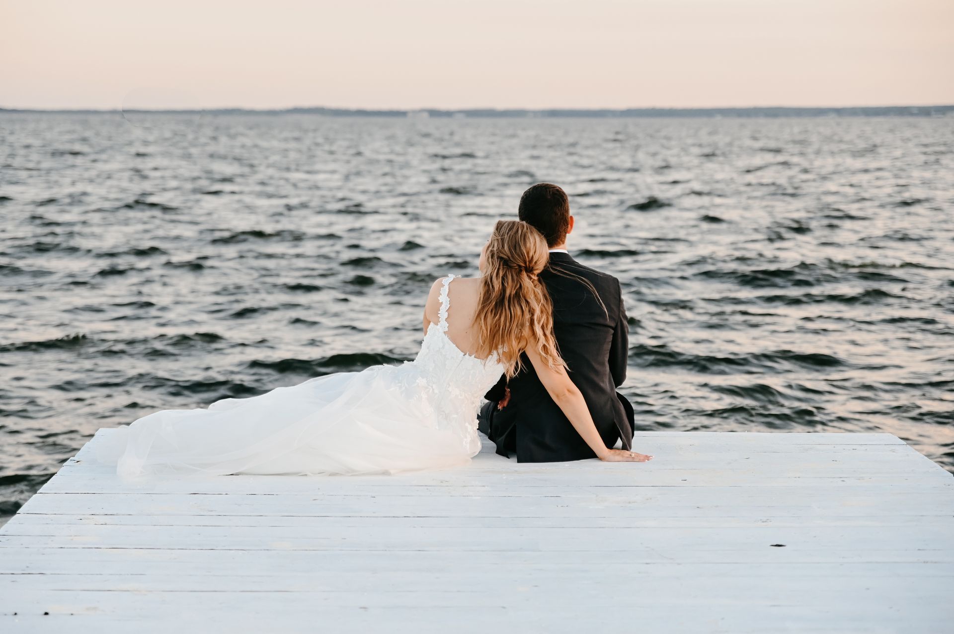 Bride and groom sitting on a dock 