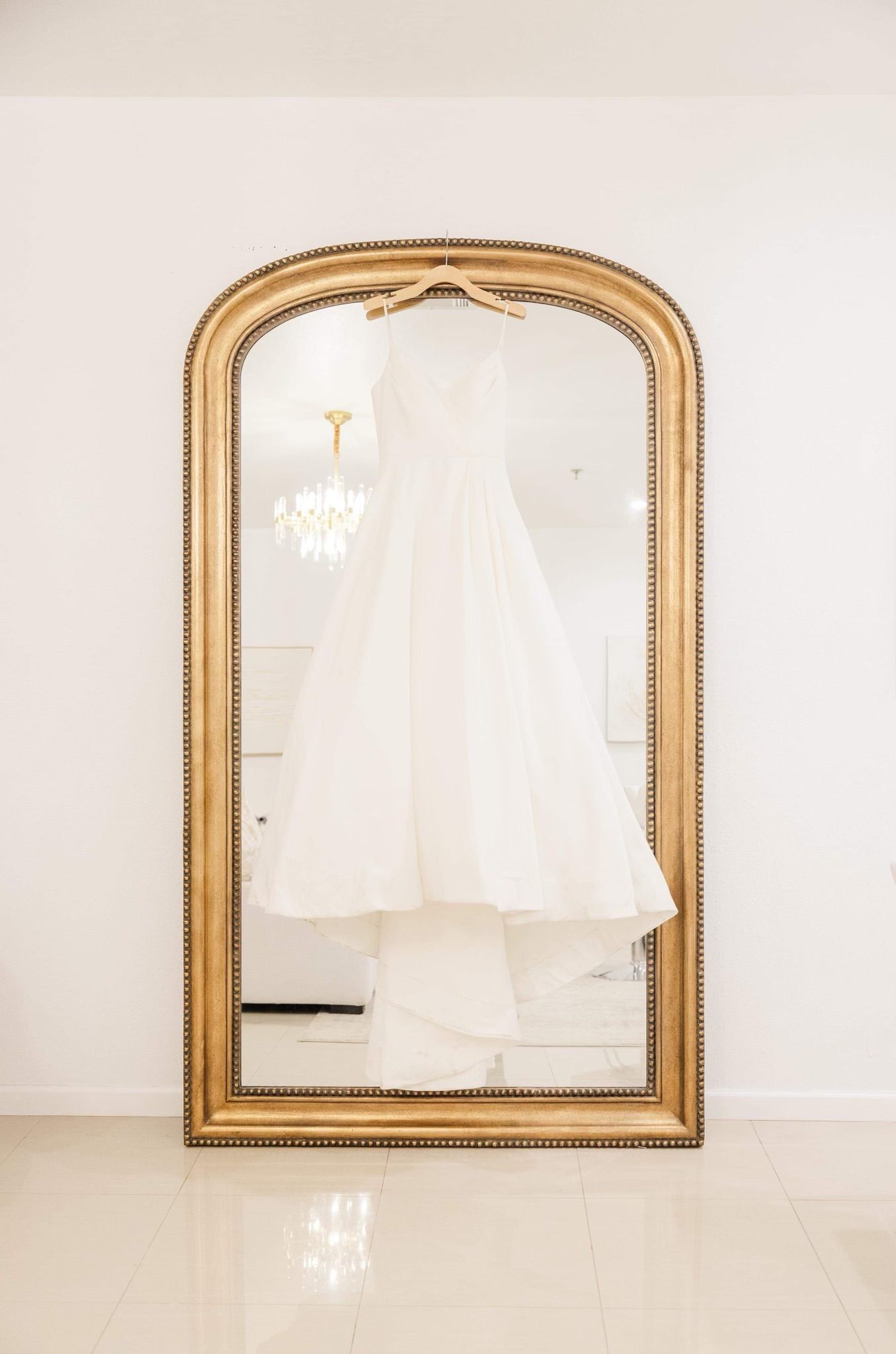 a wedding dress is hanging in front of a large mirror .