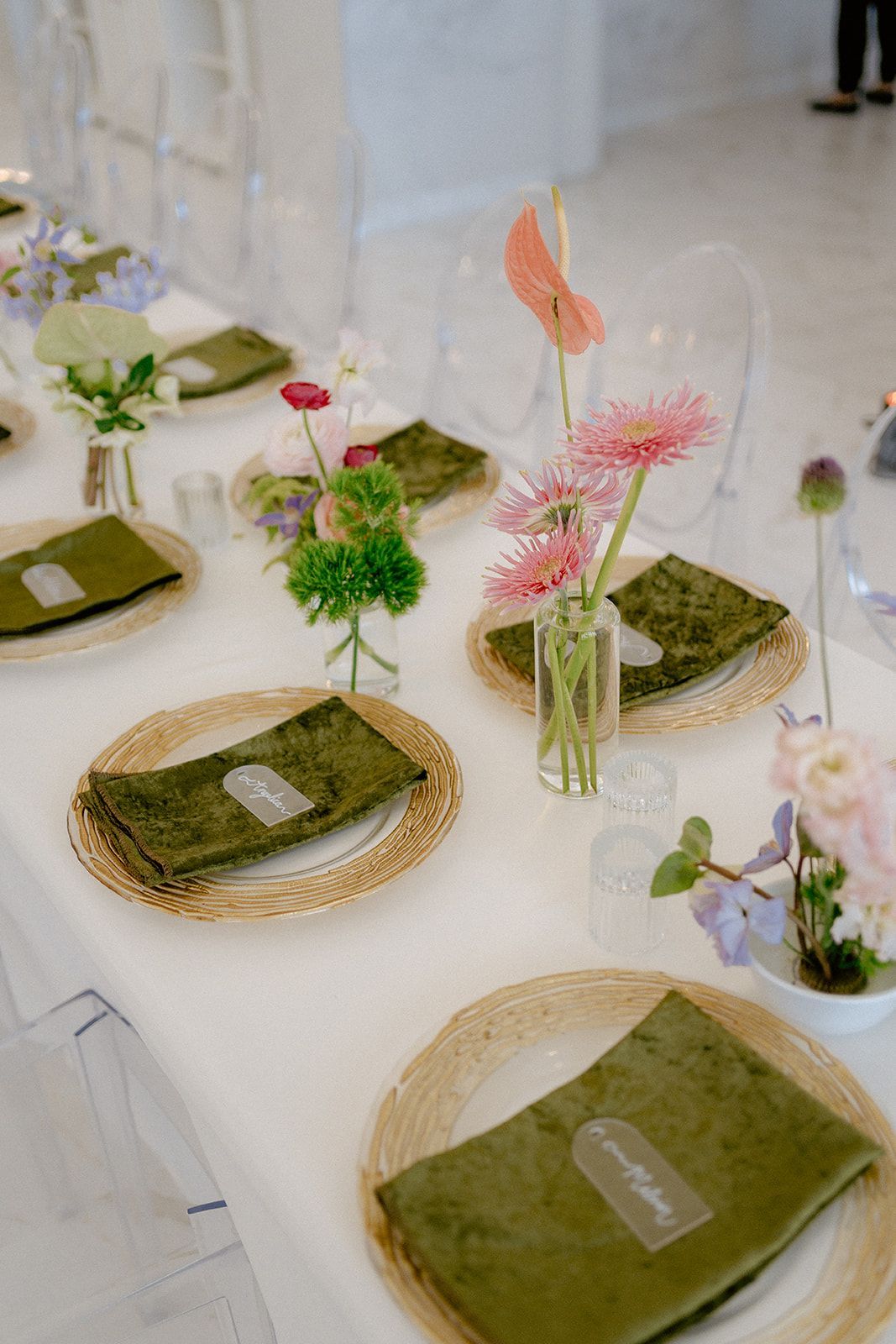 A table with plates , napkins , and vases of flowers on it.