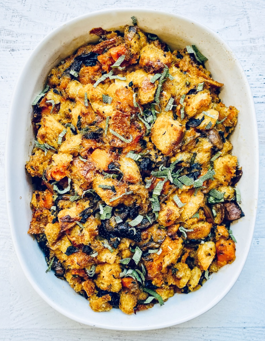 A white bowl filled with stuffing and vegetables on a table.