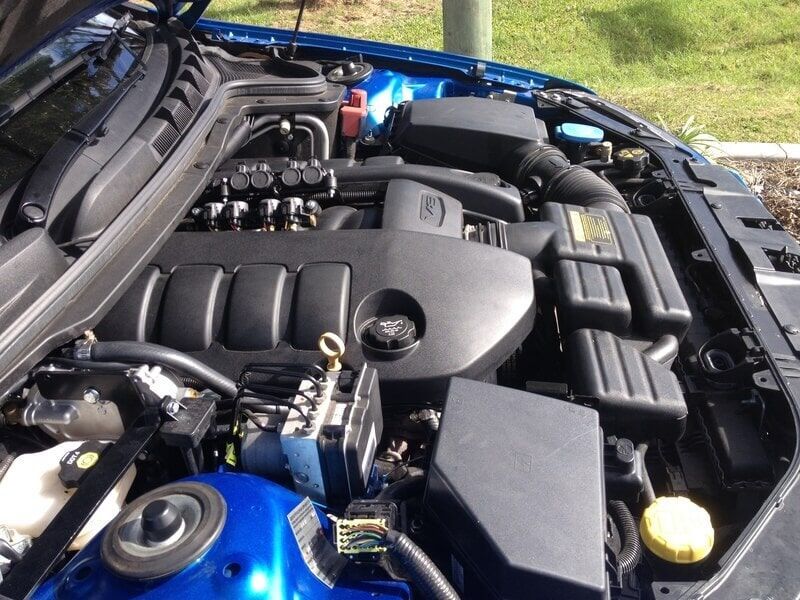 The Engine of a Blue Car is Shown With the Hood Open