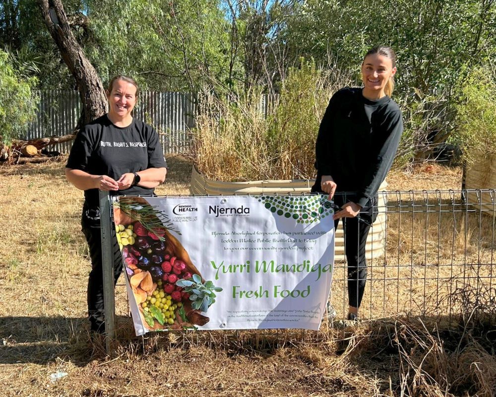 Two women stand behind a banner promoting 