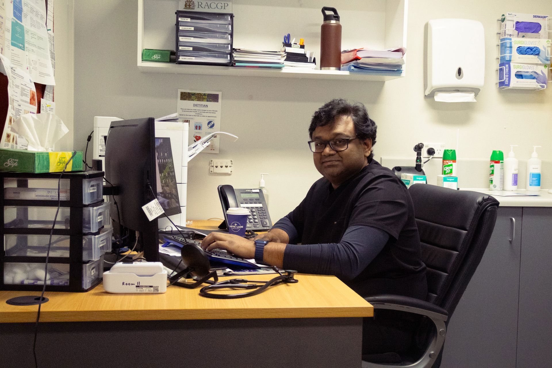 Snow-capped mountain peak illuminated by sunlight, viewed from a dark valley. Blue sky with clouds above.