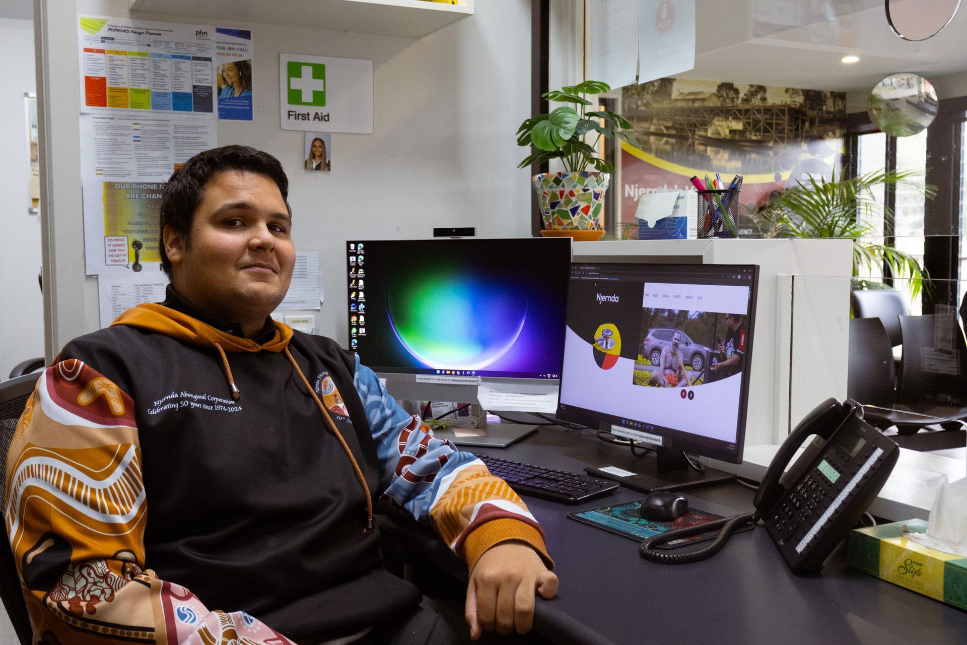 Snow-capped mountain peak glows in the sunlight, framed by dark, verdant mountain slopes under a blue sky.