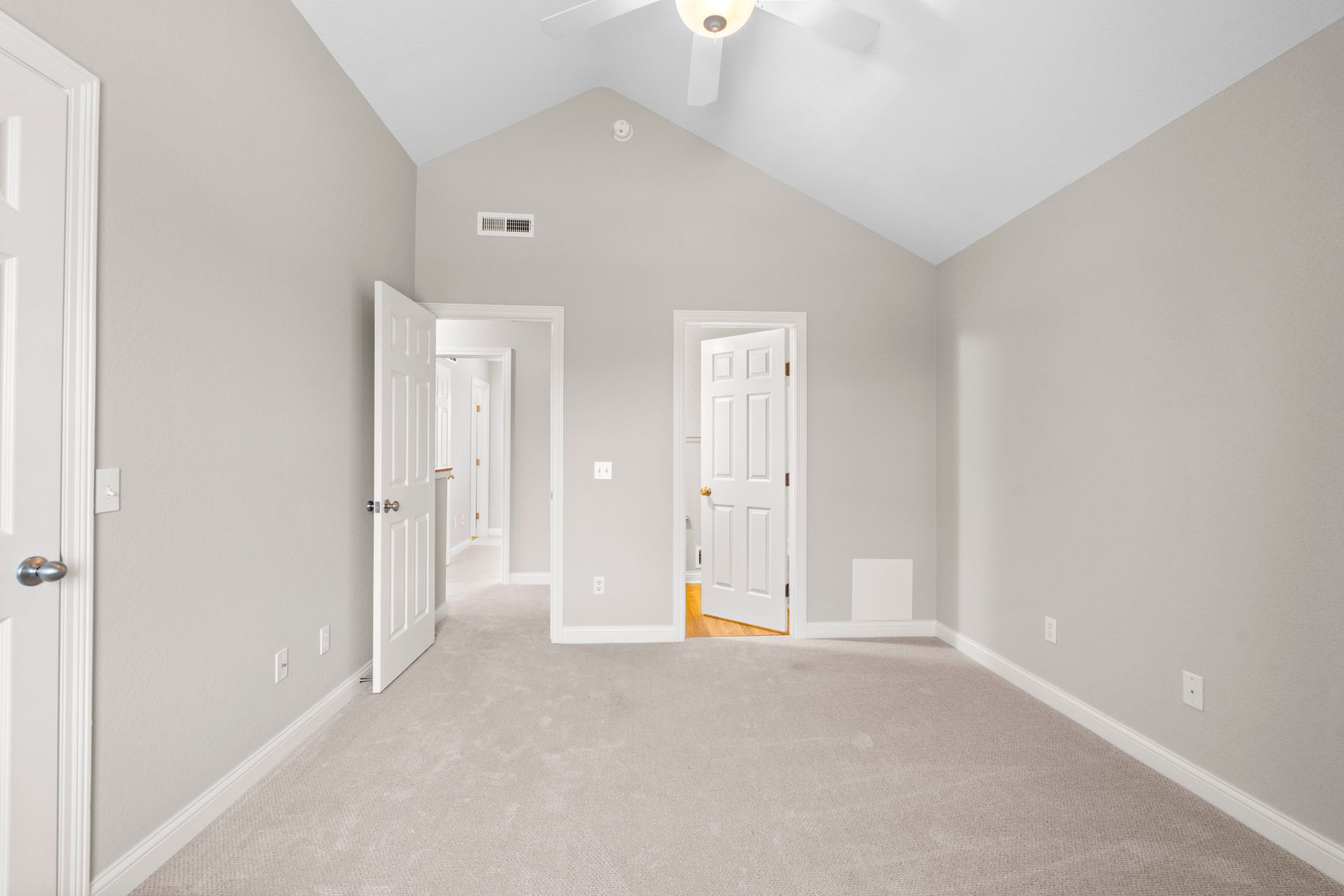Empty bedroom with gray walls, white doors, and light carpet.