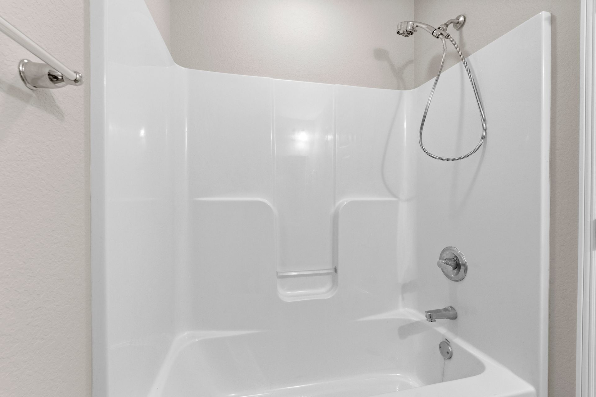 White shower/tub combo with built-in shelves and chrome fixtures.