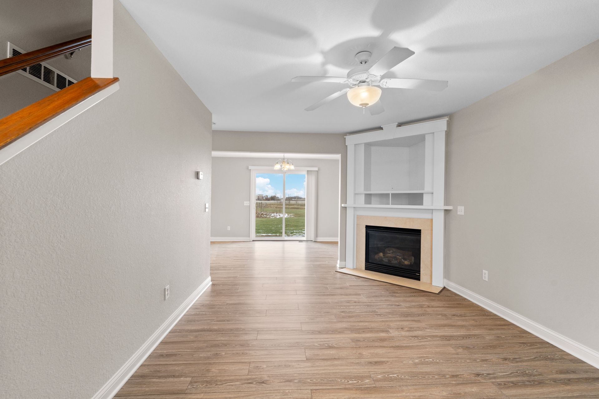 Living room with fireplace, stairs, wood floors, and a view to the outdoors.