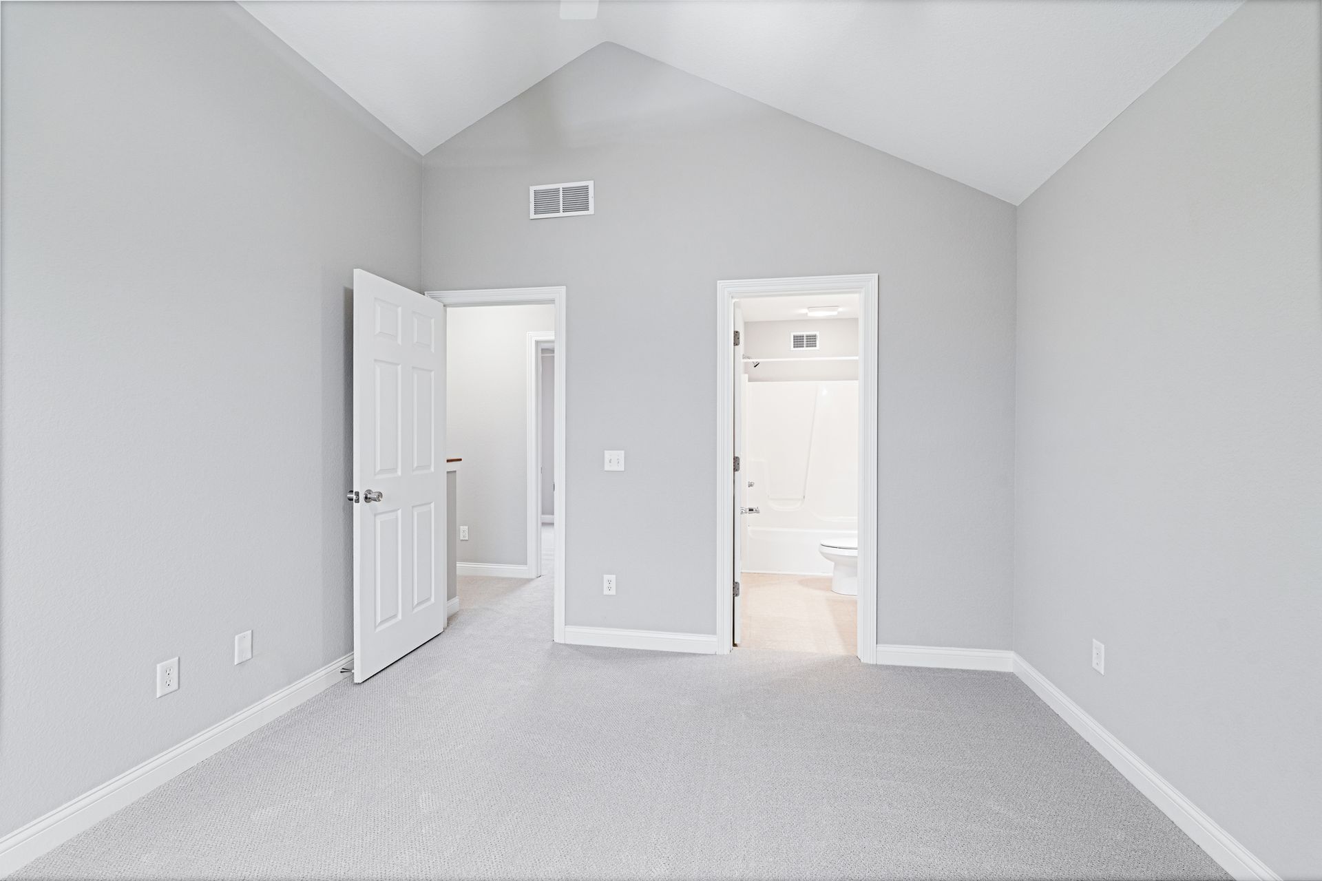 Empty bedroom with gray walls, carpet, and three white doorways.