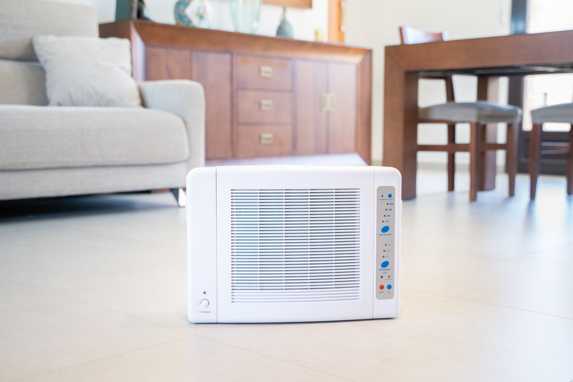 A white air purifier is sitting on the floor in a living room.