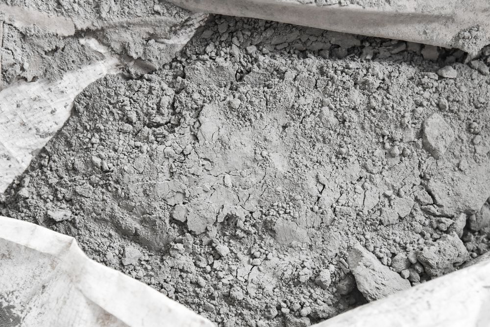 Gray Cement Powder Inside a Partially Open White Bag — Laurieton Landscape Supplies In Lake Cathie, NSW