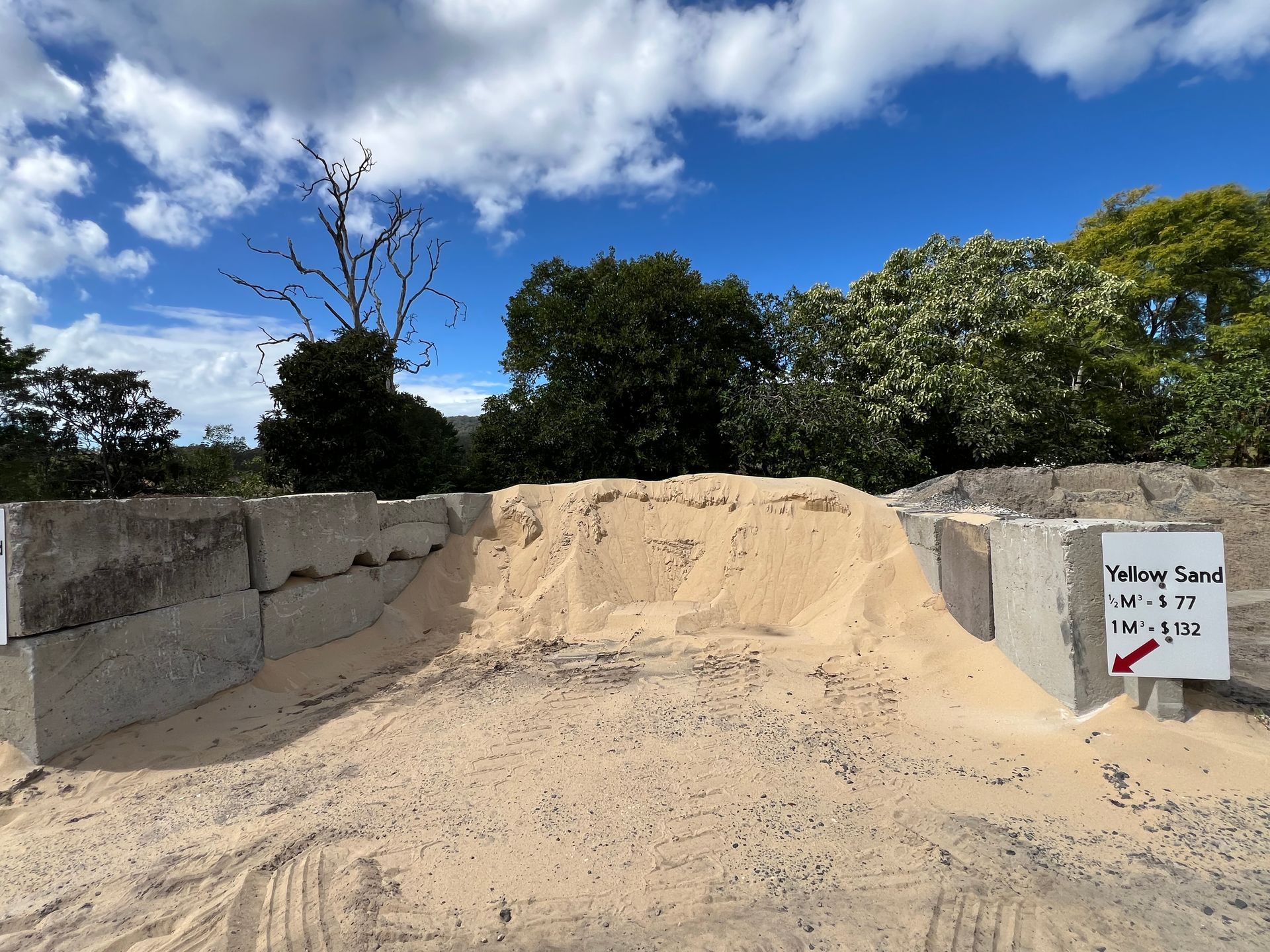 A pile of yellow sand sand sits in a stone-walled outdoor enclosure — Laurieton Landscape Supplies In Kew, NSW