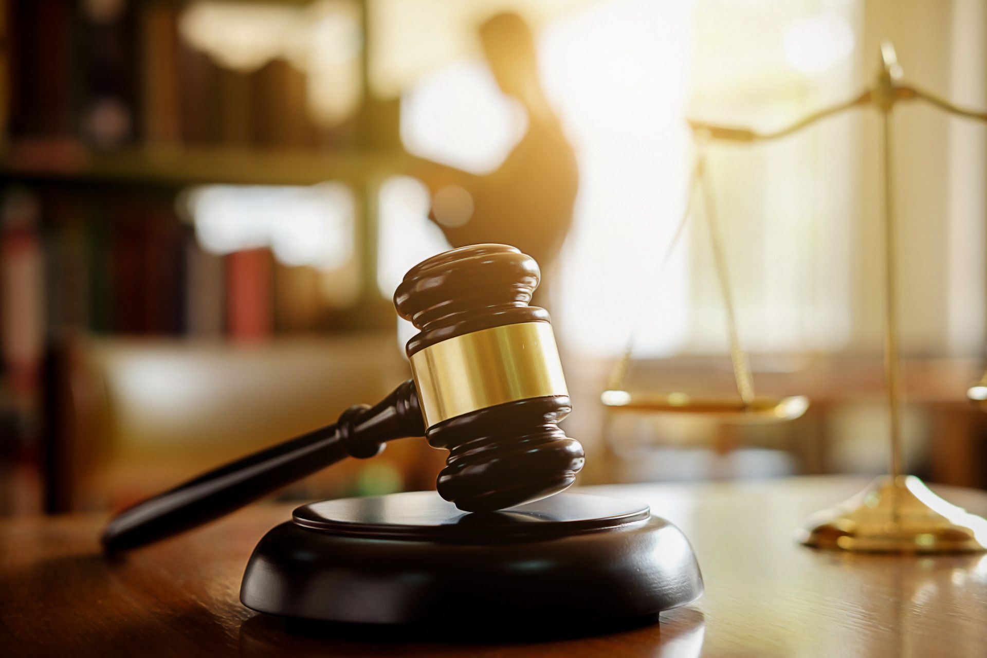 A judge's gavel is sitting on a wooden table next to a scale of justice