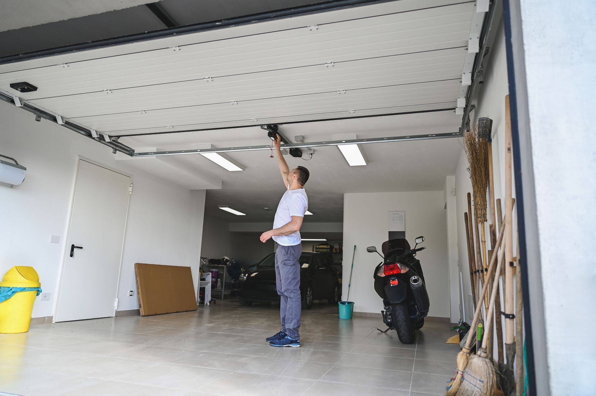 Technician performing residential garage door repair inside a home garage.