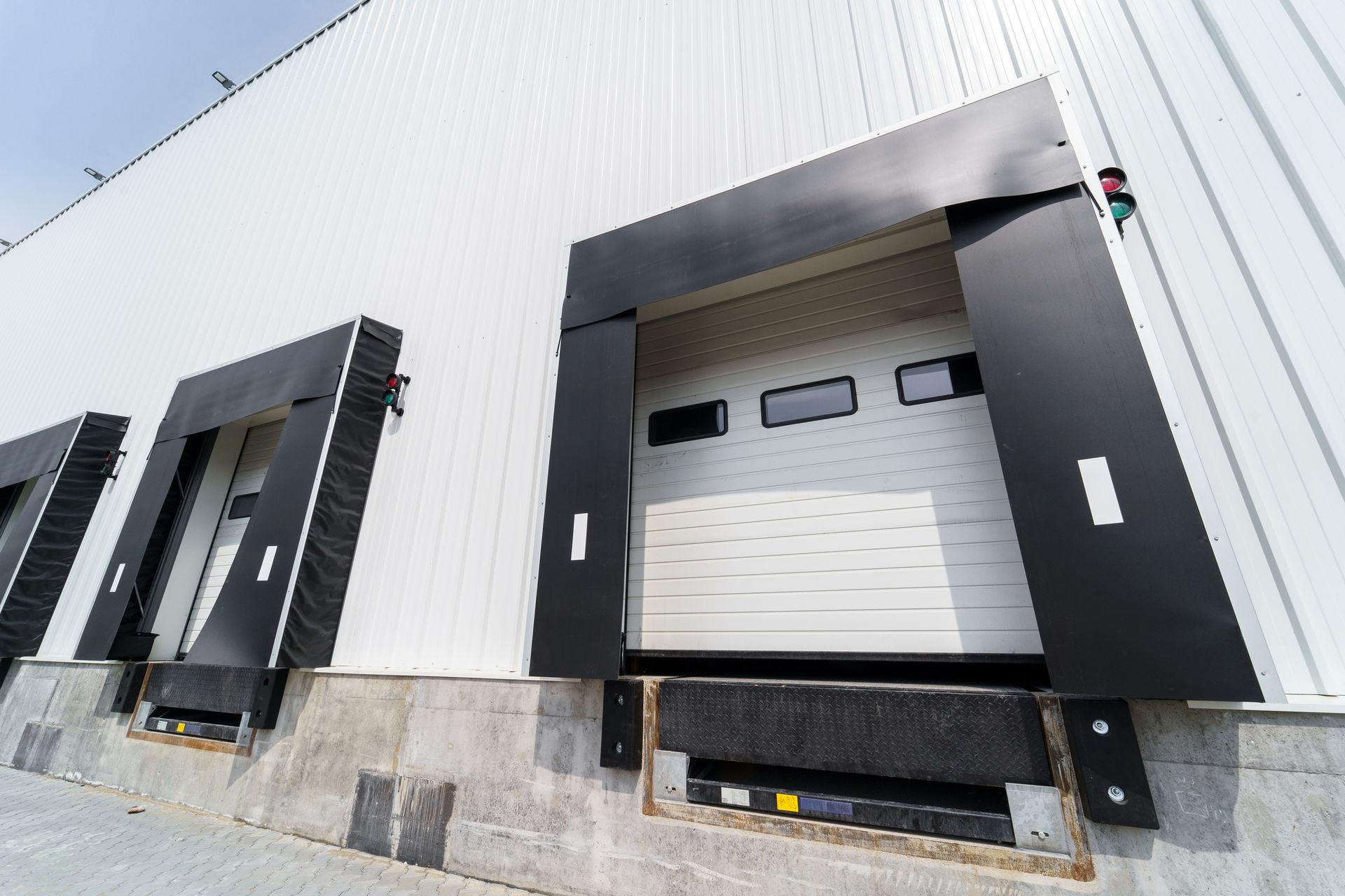 Commercial garage door with a black frame and white panels at a loading dock.
