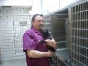 A Man In A Purple Shirt Is Holding A Dog — Columbus, OH — Oakland Park Animal Hospital