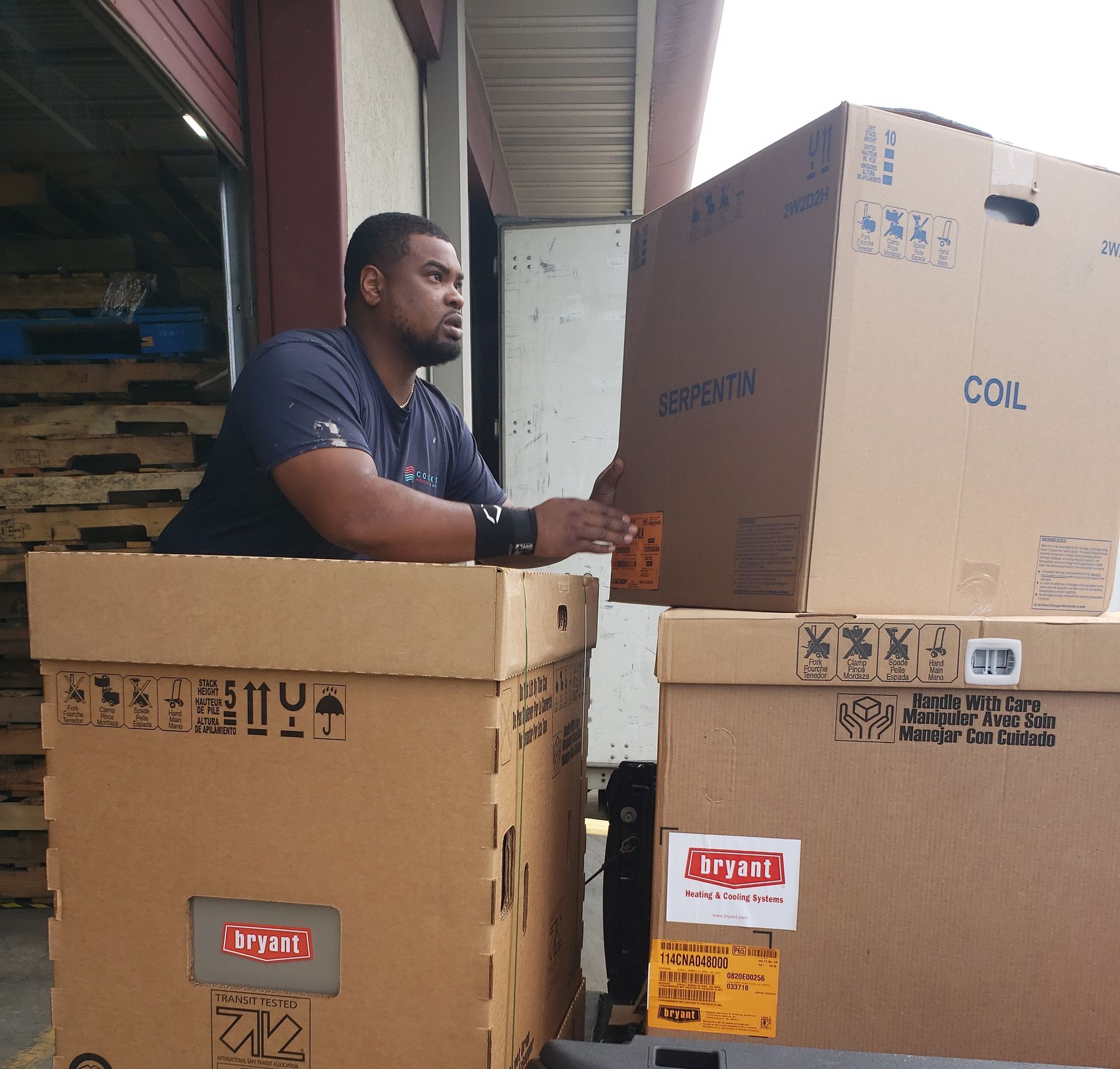 A man sits in a cardboard box with the word coil on it