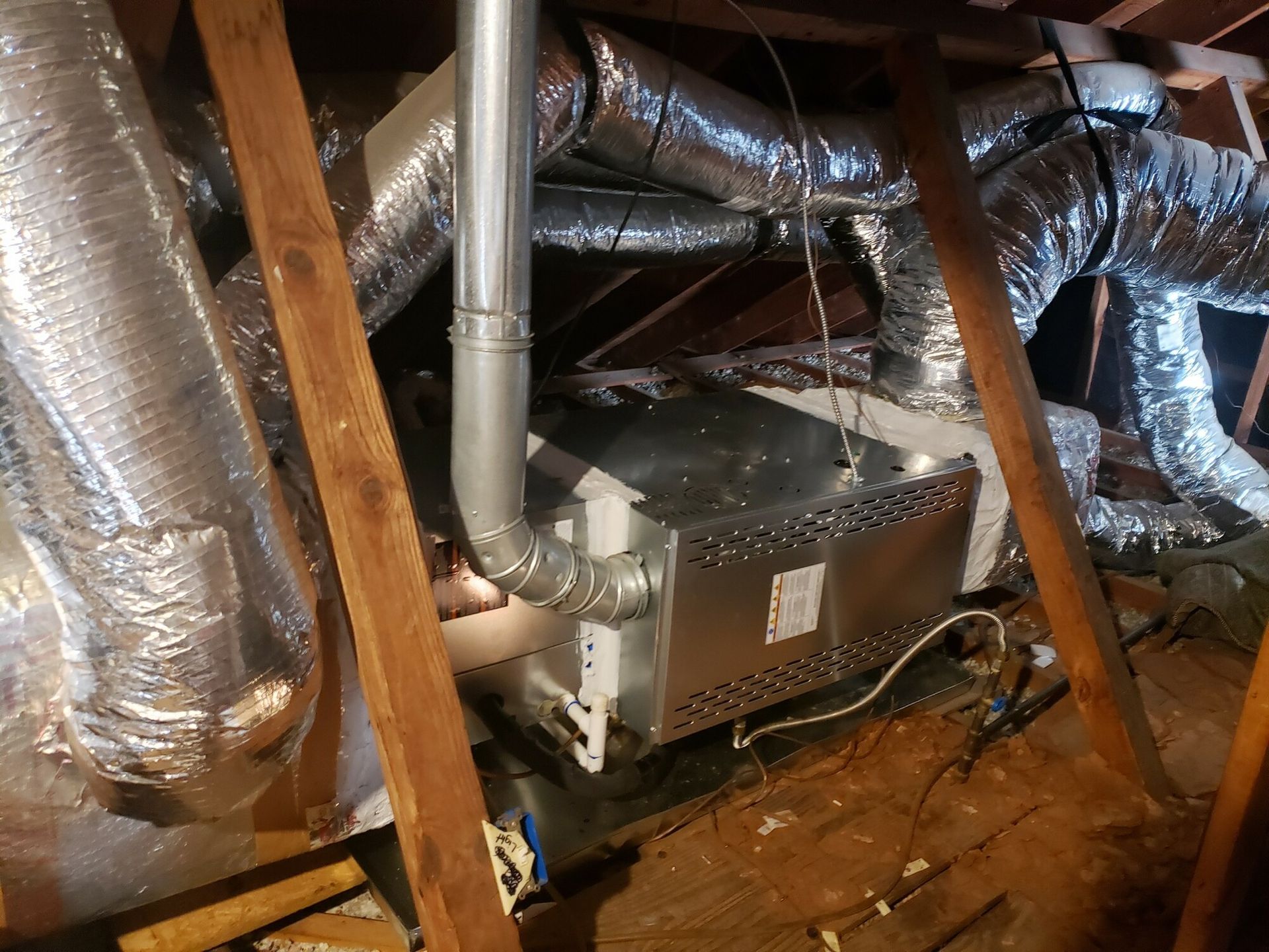A person is working on an air conditioner in an attic.