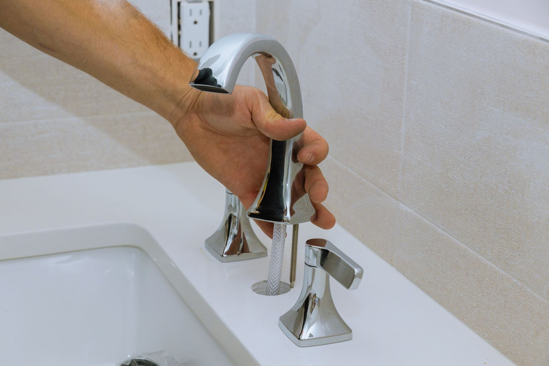 Hand turning a chrome faucet in a bathroom sink, preparing to use it.