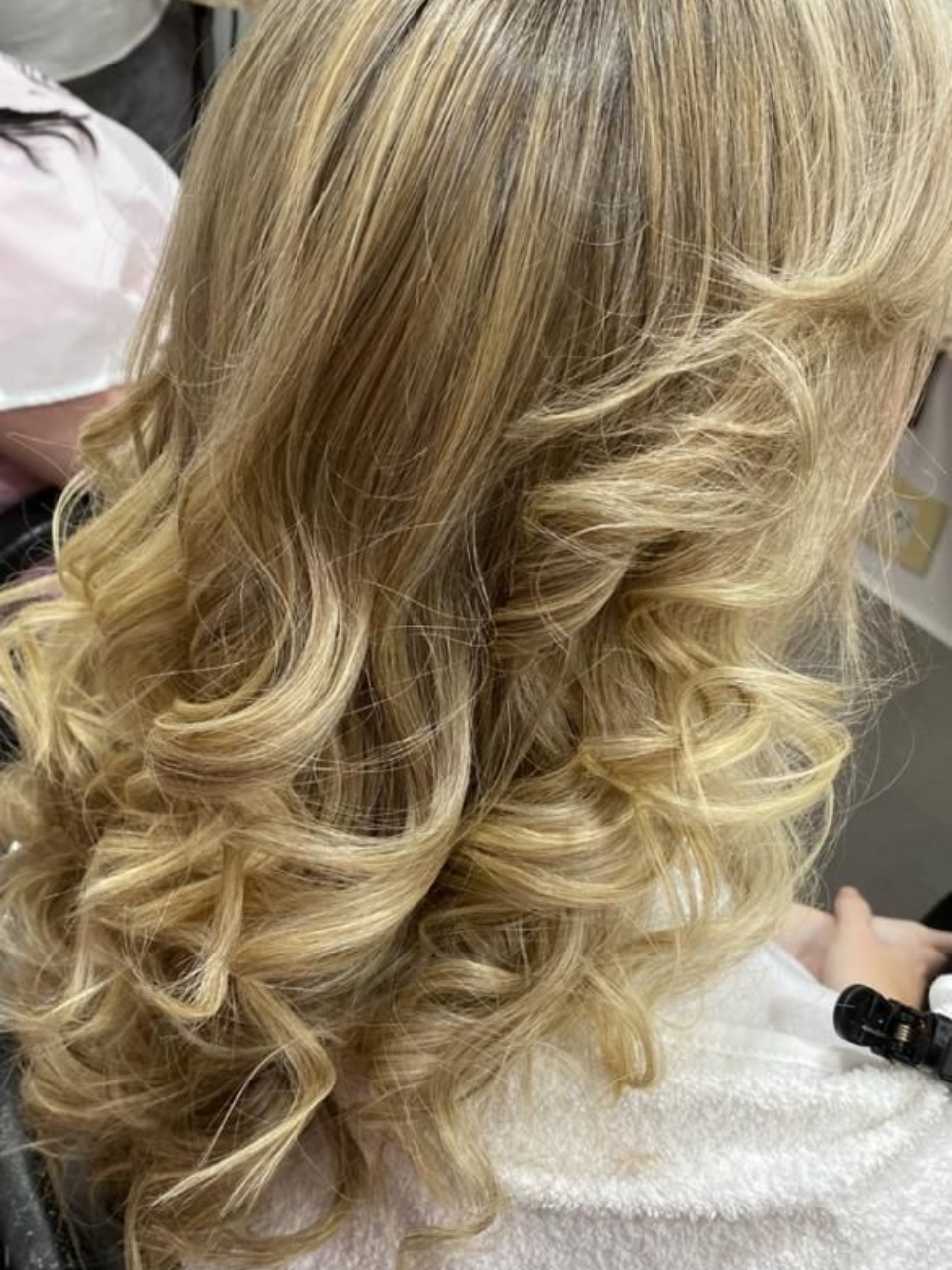 Cabello rubio de mujer peinado con rizos sueltos.