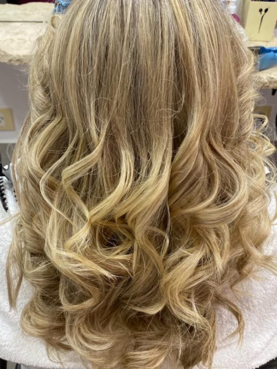 Cabello rubio de mujer peinado en rizos sueltos, vista posterior.