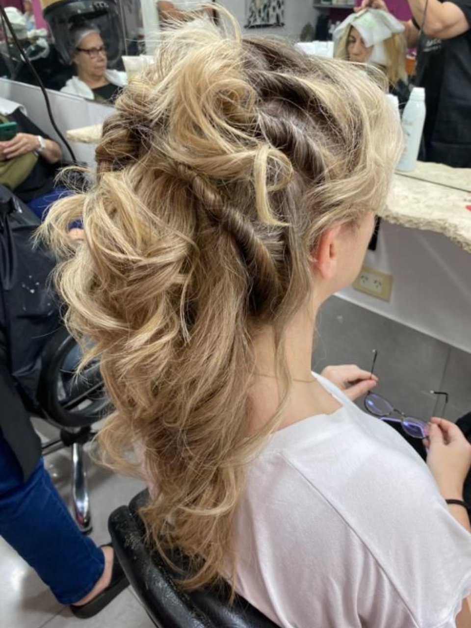 Mujer con recogido rubio en un salón, cabello peinado con rizos sueltos.
