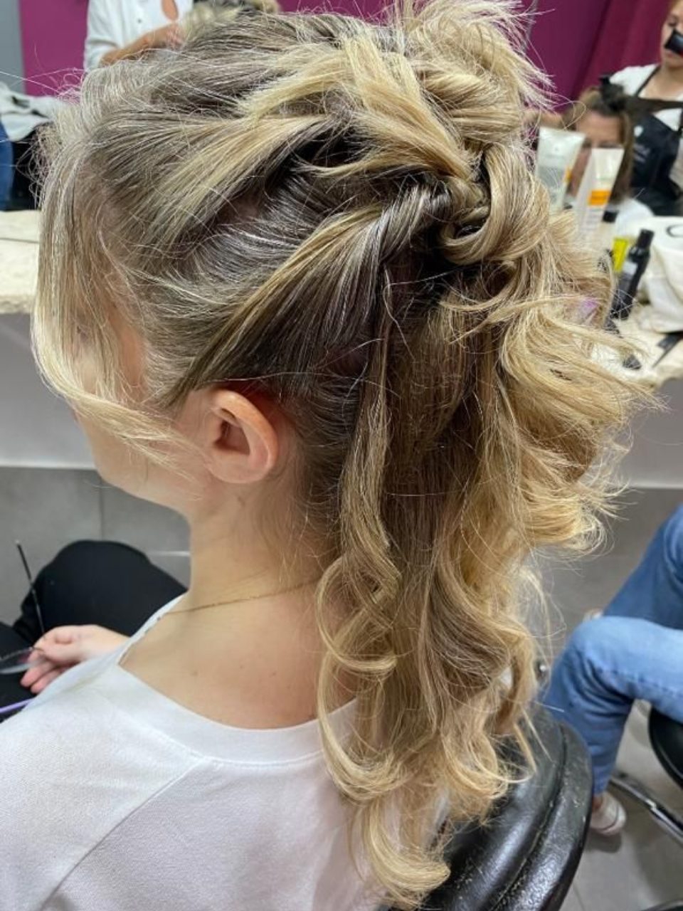 Mujer con cabello rubio en un peinado semirecogido con secciones trenzadas y rizadas.