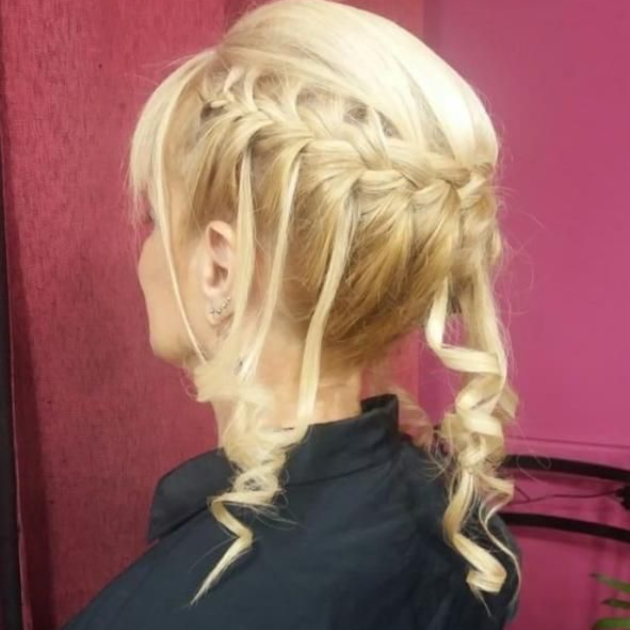 Mujer rubia con peinado recogido: trenzas y zarcillos rizados.