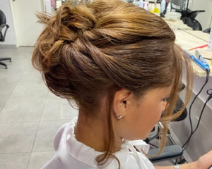 Mujer con cabello castaño claro peinado hacia arriba, probablemente para un evento, en el interior de un salón.