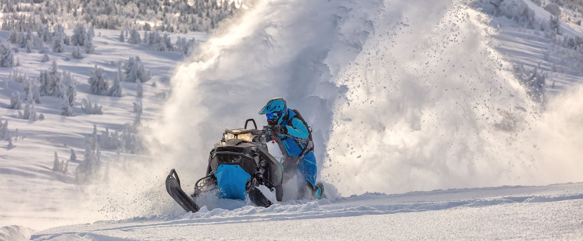 Snowmobile crash in snowy mountains, blue rider thrown into a burst of snow