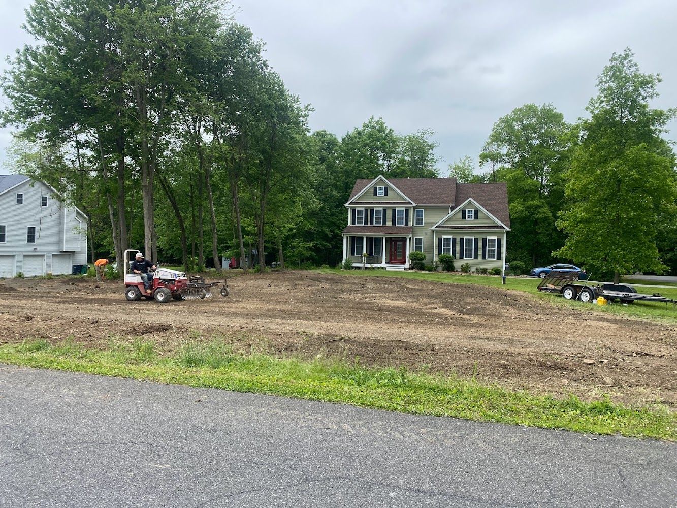 A large house is sitting on top of a dirt field next to a road.