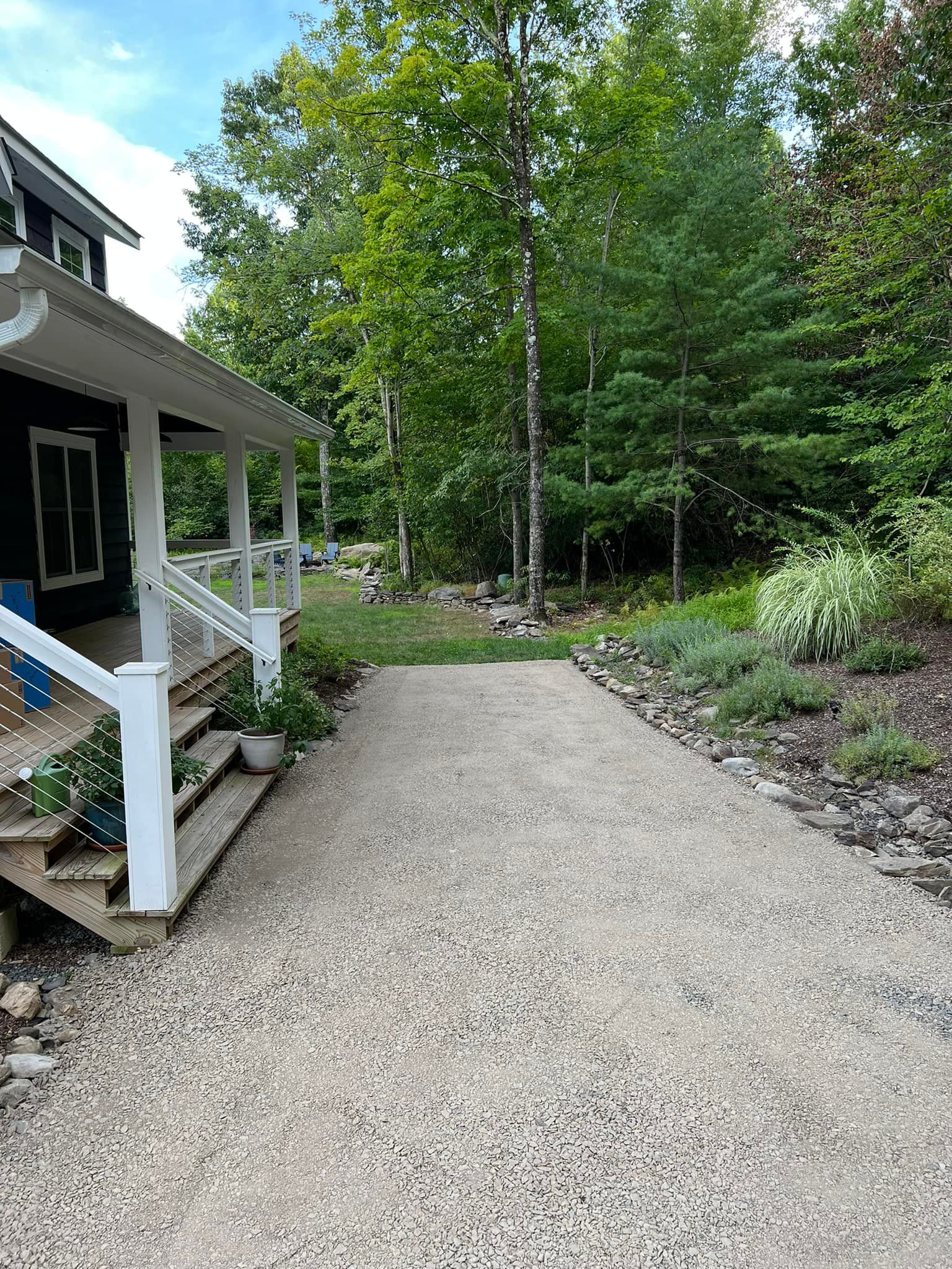 A gravel driveway leading to a house in the woods.