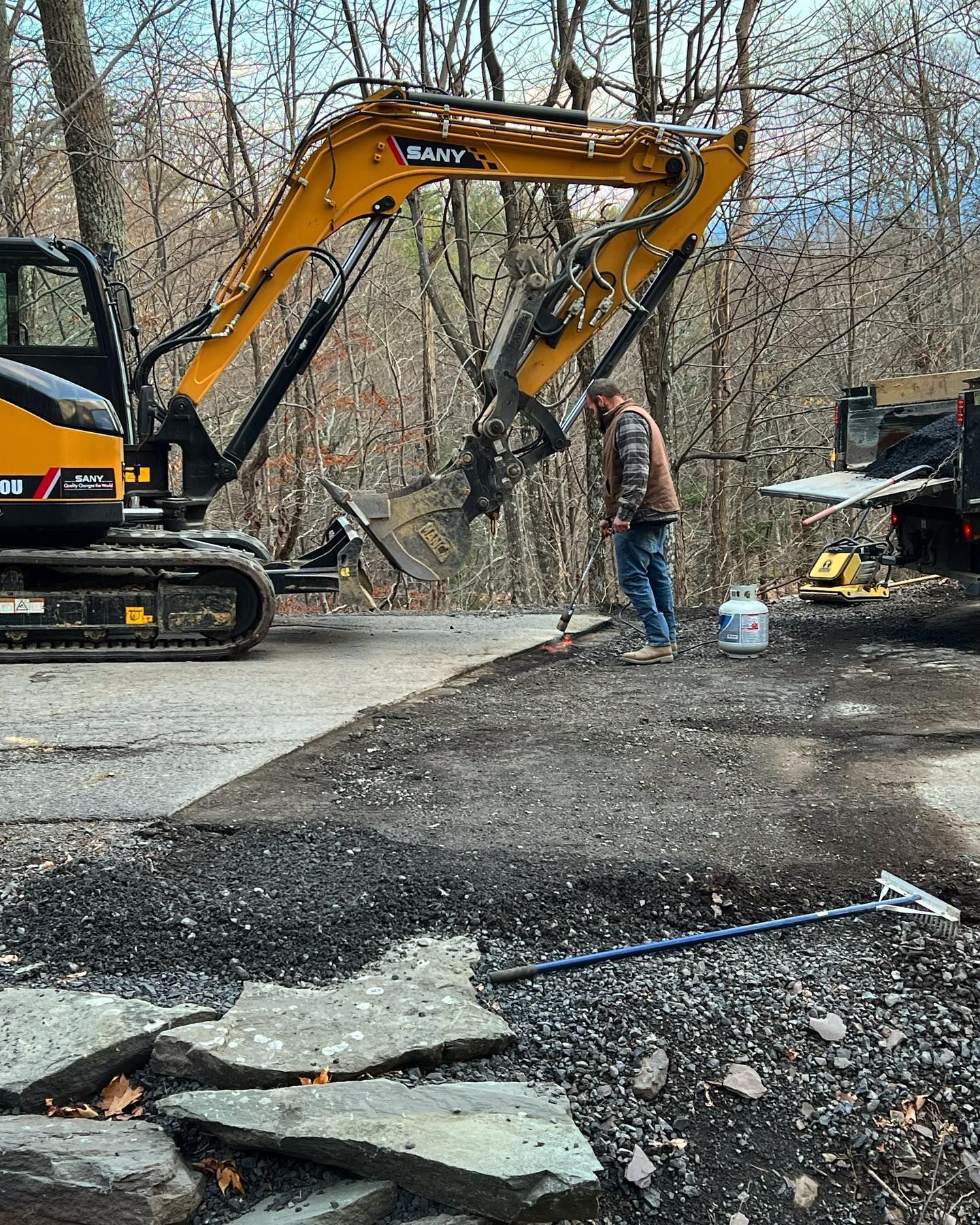 A man is standing in front of an excavator in a parking lot.