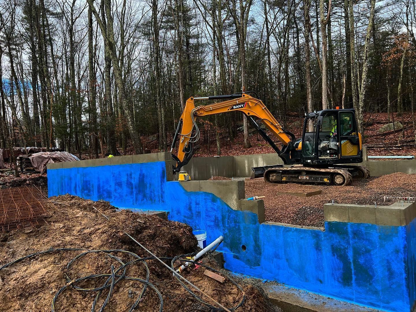 A construction site with a yellow excavator and a blue tarp.