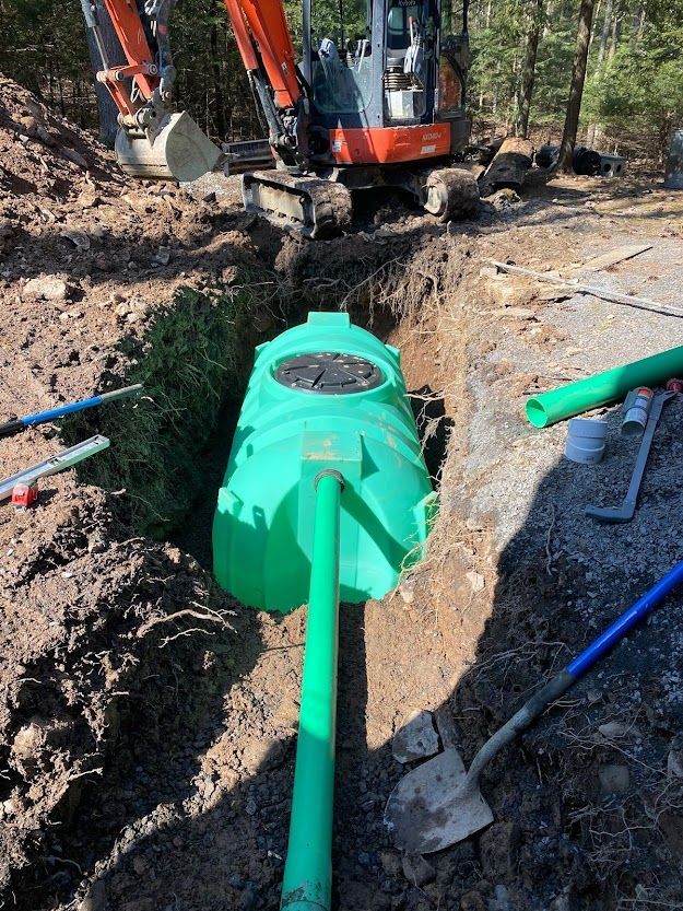 A green pipe is being installed in a hole in the ground.