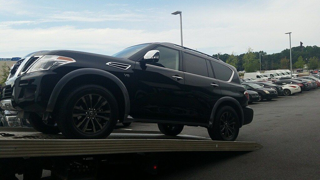 A large black nissan SUV is being towed on the back of tow truck — Best Price Towing in Woongarrah, NSW
