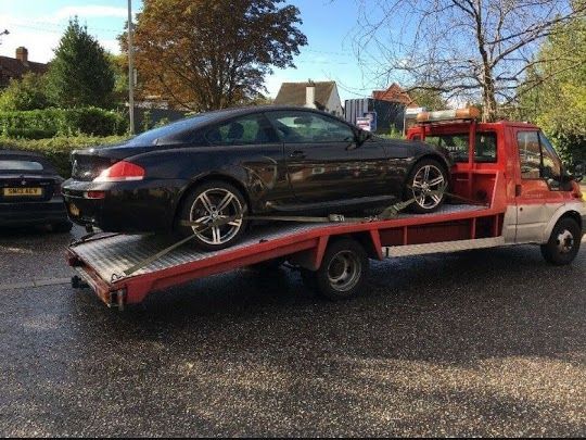 Dark Bmw Coupe Being Towed on a Red Tow Truck — Best Price Towing in Newcastle, NSW