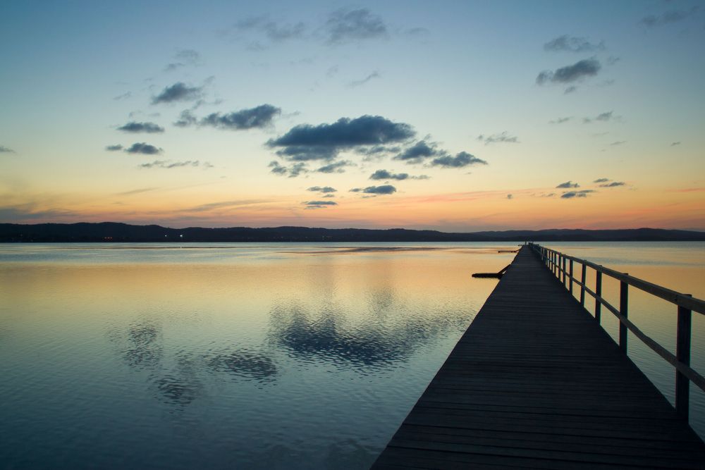 Wooden Pier Extending Into Calm Water at Dusk with Colourful Sky Reflection — Best Price Towing in The Entrance, NSW