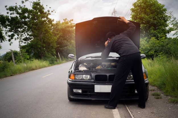 Man Looking at the Engine of a Black Car With Its Hood Open — Best Price Towing in Lake Haven, NSW