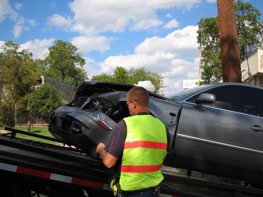 Tow Truck Driver in a Safety Vest Examines a Damaged Car — Best Price Towing in Woongarrah, NSW