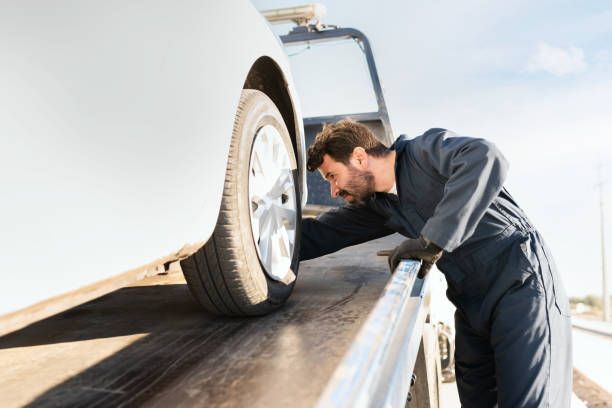 Tow Truck Driver Checks the Tire of a White Car — Best Price Towing in Budgewoi, NSW