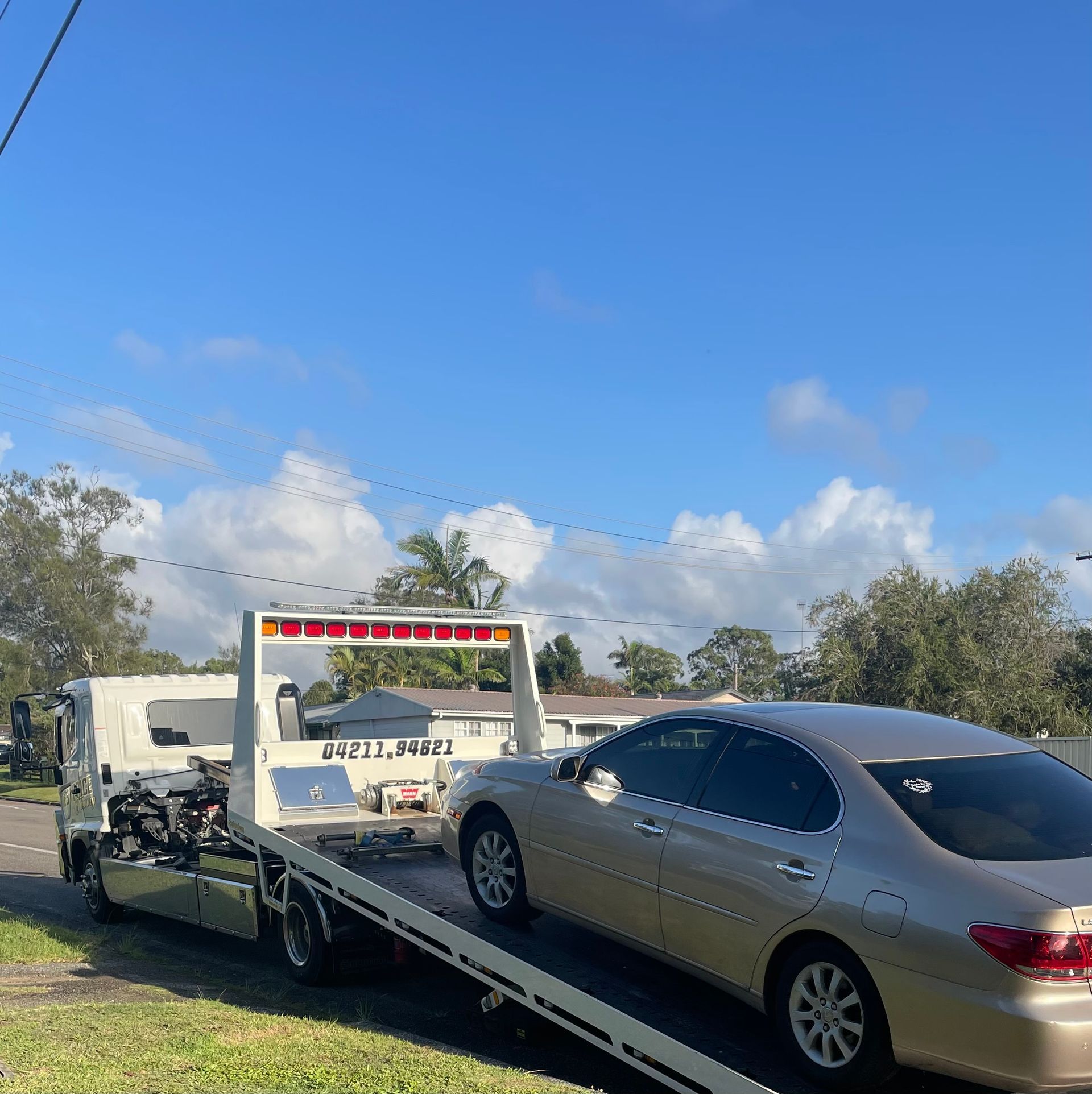 A tow truck is parked on the side of the road with a car on the back — Best Price Towing in Maitland, NSW